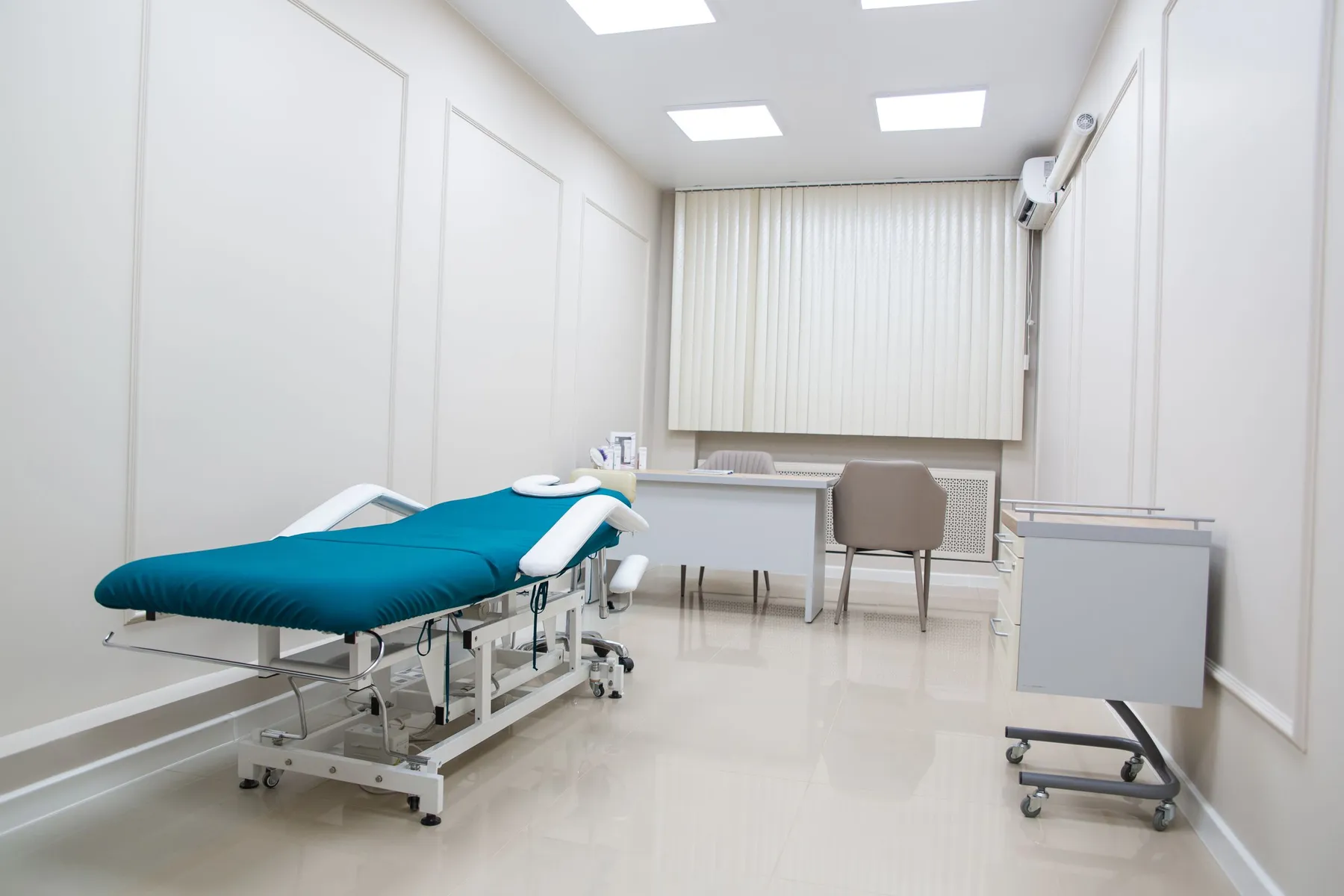 Bright, minimal clinic room with examination bed, daylight from the window