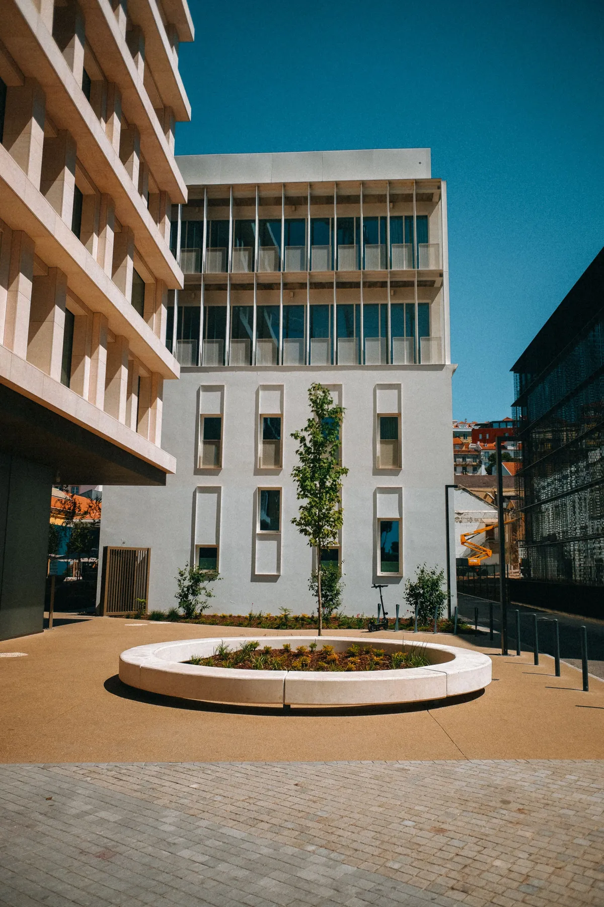 Pale building and circular planter in a courtyard, clear sky